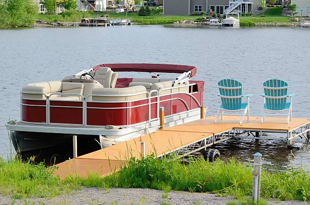 Pontoon Boat Tied to a Dock Red Pontoon Boat Tied to a Dock With Two Chairs pontoon boat stock pictures, royalty-free photos & images