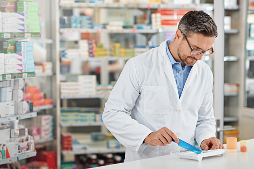 Shot of a pharmacist counting medication. All products have been altered to be void of copyright infringements