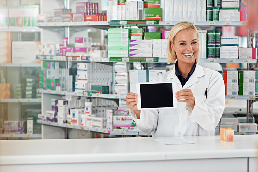 Shot of a pharmacist holding up a digital tablet. All products have been altered to be void of copyright infringements