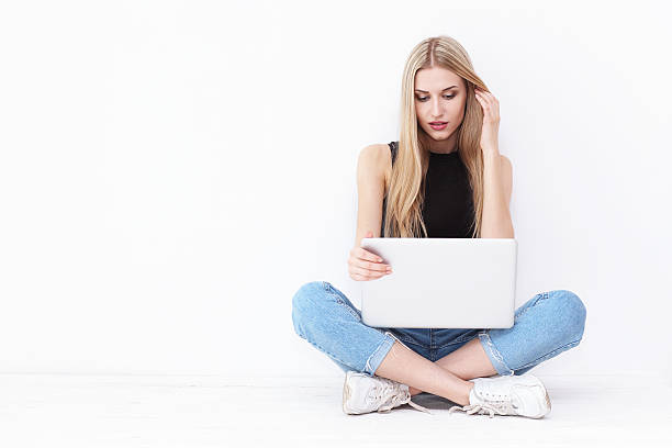 istock Happy young woman sitting on the floor and using laptop 537281198