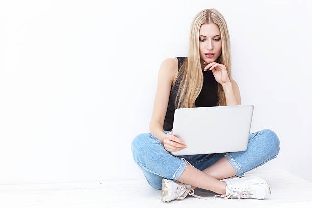 istock Happy young woman sitting on the floor and using laptop 537281392