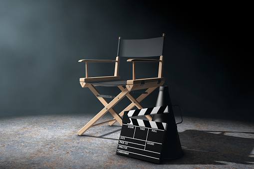 Director Chair, Movie Clapper and Megaphone in the volumetric light on a black background. 3d Rendering