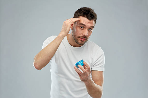 happy young man styling his hair with wax or gel stock photo