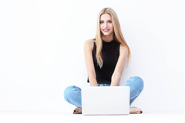 istock Happy young woman sitting on the floor and using laptop 537283040