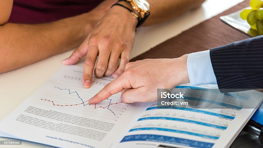 Financial graph Business colleagues working together and analyzing financial figures on a graphs. Adult Stock Photo