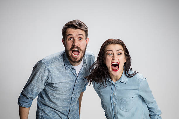 The screaming man and woman looking at camera on gray background