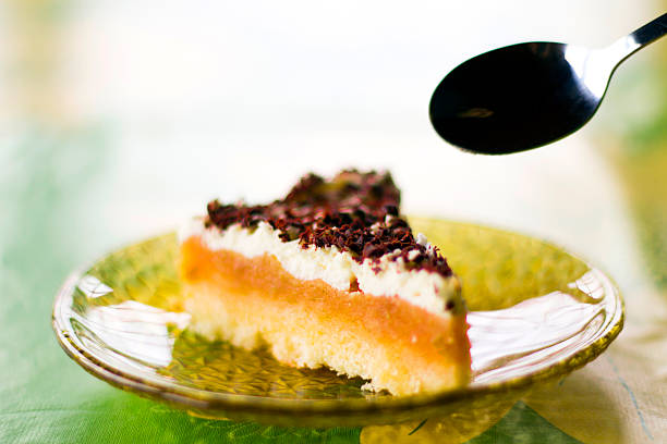 Piece of apple pie with delicious whipped cream and chocolate on the top. Someone is going to eat it with the spoon.