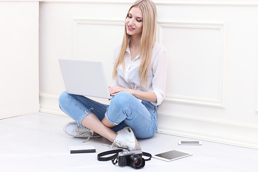 Mujer joven sentado en el piso con su computadora portátil, photo