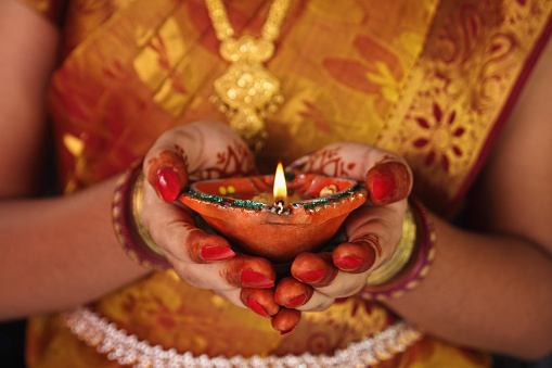     Indian Girl Holding Traditional Oil Lamp with Flame