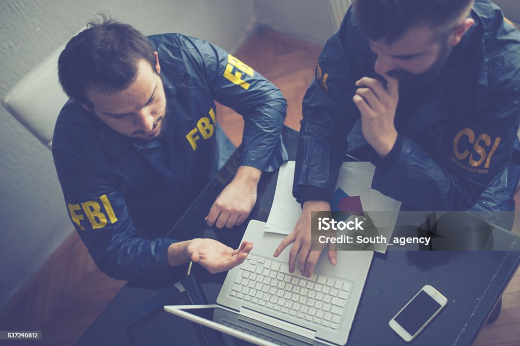 FBI and CSI agents FBI and CSI agents working in the office on a crime. they are working on laptop FBI Stock Photo