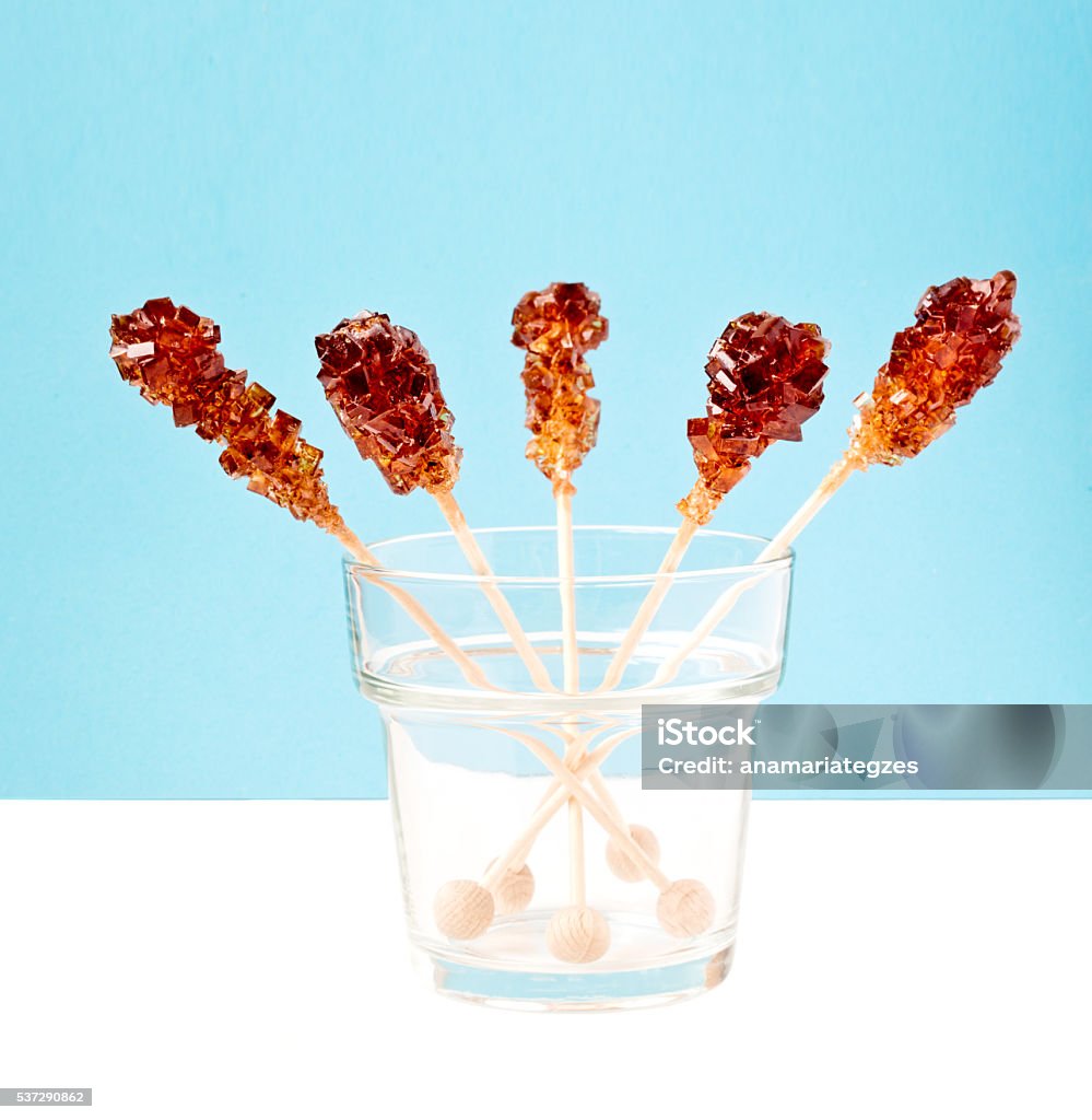 Five Brown Sugar Stirrers Five brown sugar stirrers in a glass on a white table with light blue background. Amber Stock Photo