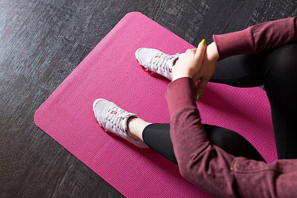 istock Woman in running shoes sitting on an exercise mat. 537294484