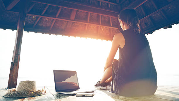 istock Freelancer sitting at sunset near the ocean with laptop 537302142