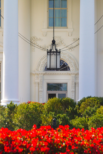 North Portico Of The White House in Washington DC. There are beautiful red flowerbeds and a lantern in the porch.