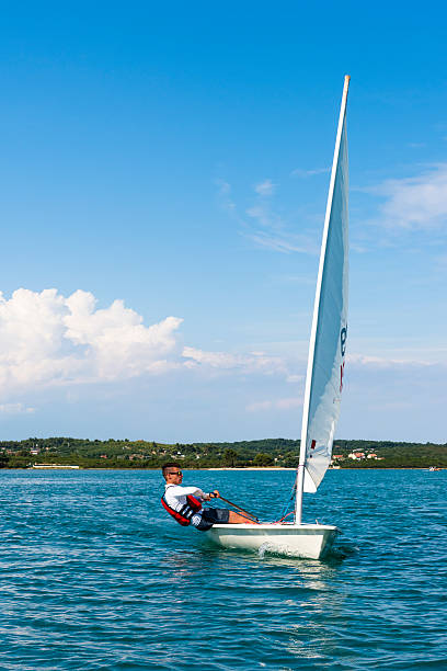 Young Man Sails a Laser Olympic  Class Sailing Boat Side view of young male boats-man sailing on laser class sailing boat sailing dinghy stock pictures, royalty-free photos & images