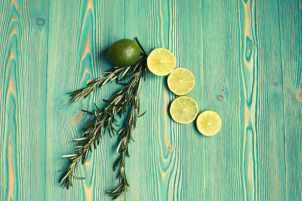 Lime and rosemary on blue-green wooden table, toned