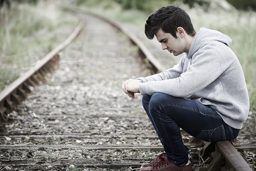 Depressed Young Man Sitting On Railway Track