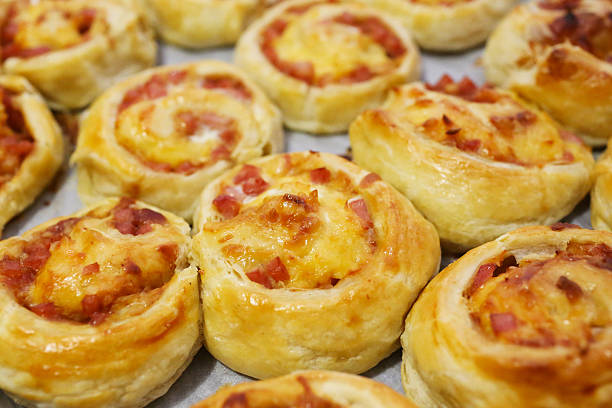 rolled baking of puff-paste with cheese and ham rolled baking of puff-paste with cheese and ham on baking pan biscuit quick bread photos stock pictures, royalty-free photos & images