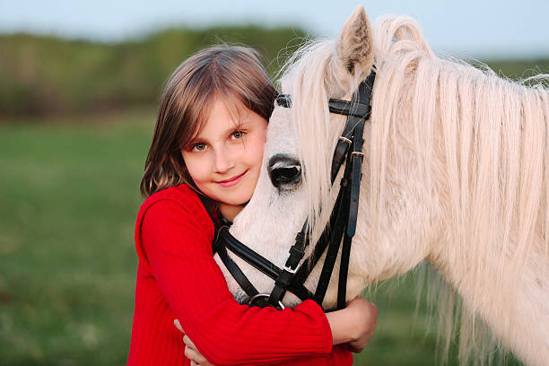 Little young girl red dress hugging his head white horse stock photo