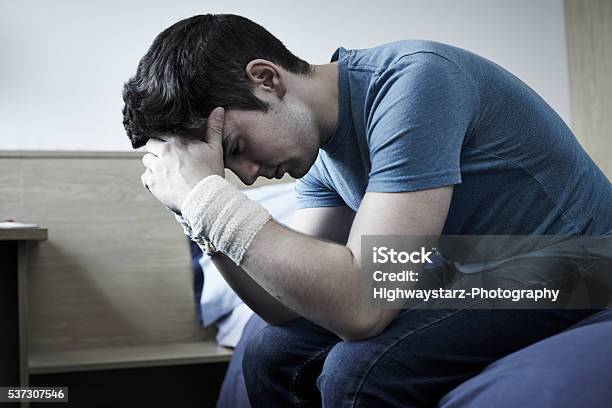 Depressed Young Man With Bandaged Wrists After Suicide Attempt Stock Photo - Download Image Now