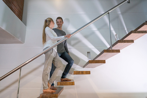 Casual couple relaxing at home and climbing up the stairs - bedtime concepts