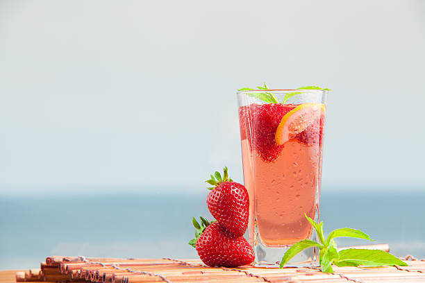 Glass of strawberry lemonade with pieces of strawberry, lemon and fresh mint. stock photo