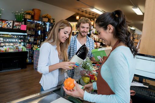 Happy couple grocery shopping at the supermarket and paying at the cashier