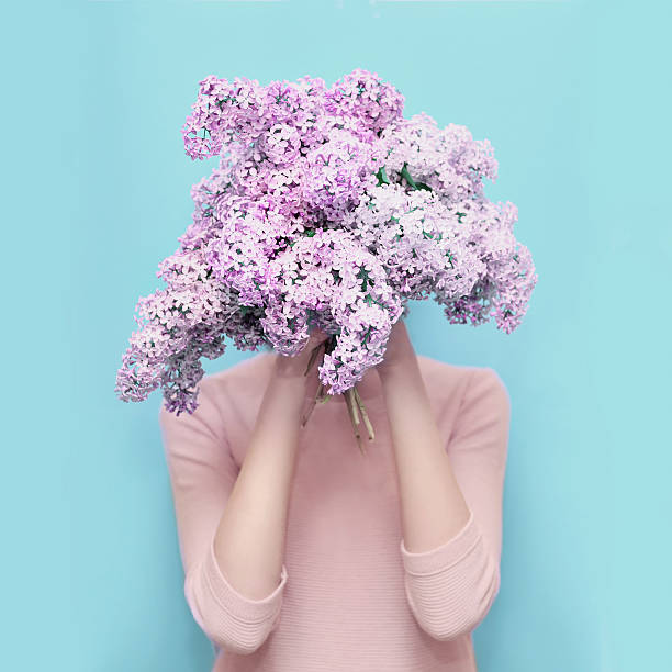 femme cacher tête de bouquet coloré de fleurs lilas sur bleu - hands in head photos et images de collection