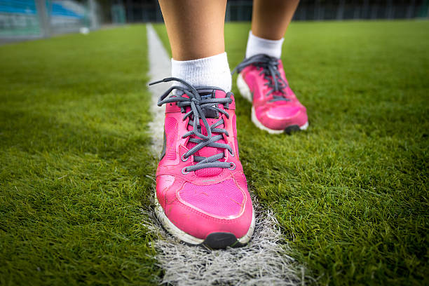 istock woman in pink sneakers running on fresh grass 537315563