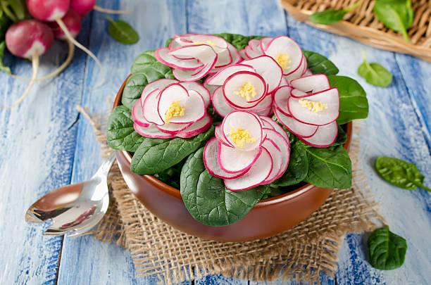 Vegetable salad Violet on blue wooden table. Salad decorated with flowers from radish and spinach leaves