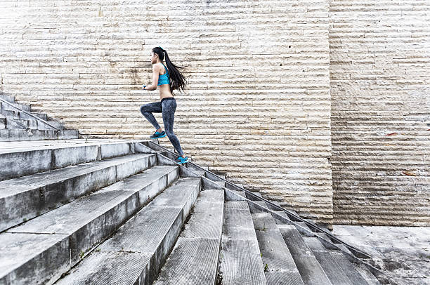 istock Female athlete running up on stairs-side view 537316296