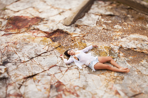 View of a young woman washed up on rocks at the edge of a river, possible boating accident victim
