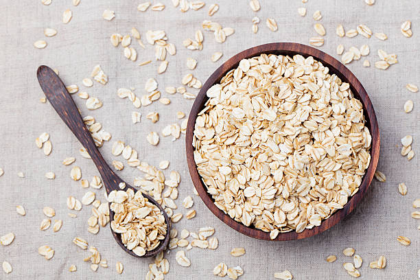 gesundes frühstück mit bio-hafer-flocken im holzschüssel - oatmeal stock-fotos und bilder