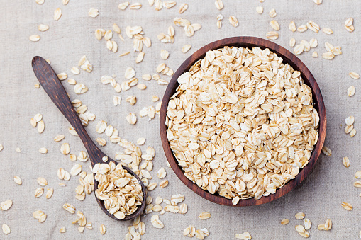 Healthy breakfast Organic oat flakes in a wooden bowl Grey textile background Top view Copy space