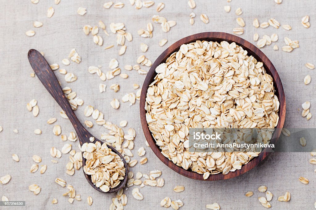 Healthy breakfast Organic oat flakes in a wooden bowl Healthy breakfast Organic oat flakes in a wooden bowl Grey textile background Top view Copy space Oats - Food Stock Photo