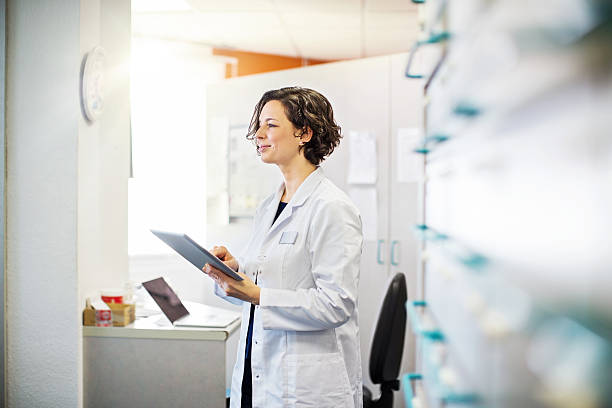 Female pharmacist with a digital tablet Female pharmacist with a digital tablet standing at chemist store doctor lifestyle stock pictures, royalty-free photos & images