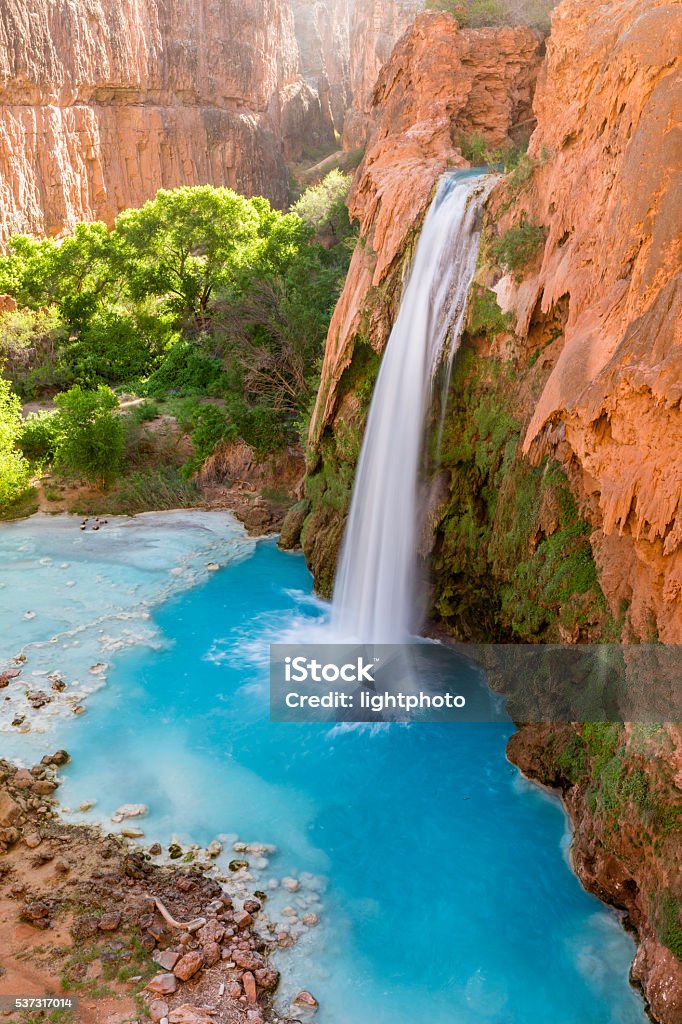 Havasu Falls Tranquility Havasu Falls plunges into a deep blue-green pool, with Cataract Canyon behind lit by the morning sun, on Havasupai Indian Reservation in the Grand Canyon. Havasu Falls Stock Photo