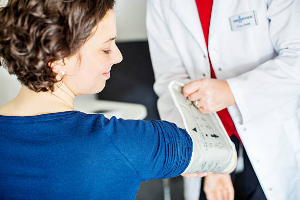 infirmière vérification de la pression artérielle de jeune femme - medical check photos et images de collection