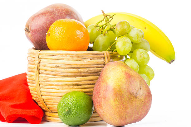 Fruit in Unique Spiral Woven Basket Lovely vintage cane basket woven in spiral pattern and containing assortment of fruit on white background with copy space. antique fruit bowl stock pictures, royalty-free photos & images