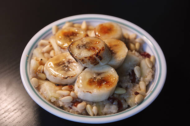 Oat porridge with pine nuts and torched bananas stock photo