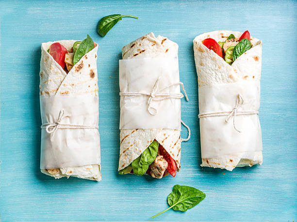 Healthy lunch snack. Tortilla wraps with grilled chicken fillet and Healthy lunch snack. Tortilla wraps with grilled chicken fillet and fresh vegetables on blue painted wooden background. Top view wrap sandwich photos stock pictures, royalty-free photos & images