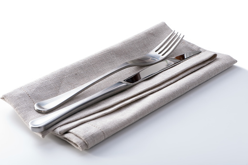 cutlery with linen napkin on white background