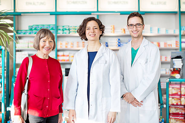 istock Young pharmacists standing with senior customer 537327950