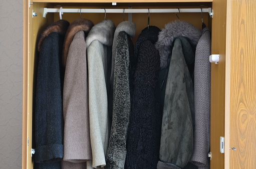 Women's wool and fur coats hanging in the wardrobe.