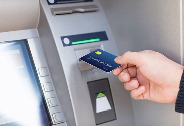man puts credit card into ATM stock photo