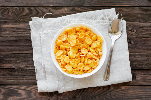 Tasty corn flakes in bowl. Rustic wooden background.