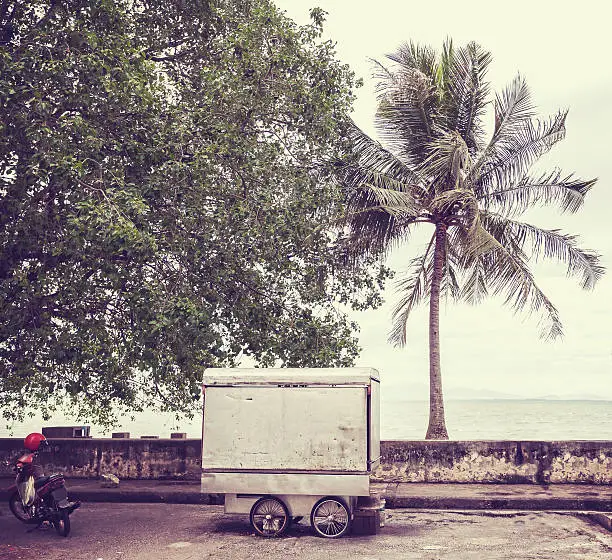 Photo of Retro filtered picture of food cart on seaside street.