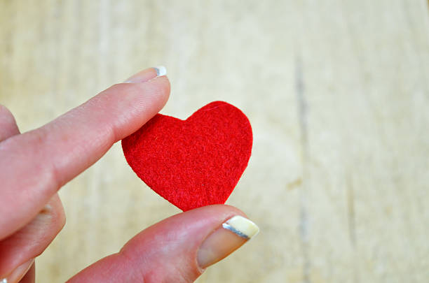istock Tiny red heart held by women's fingers 537346353