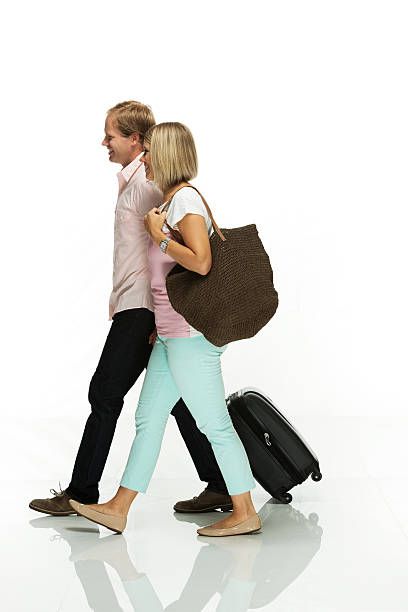 Smiling couple holding trolly bag & walking Smiling couple holding trolly bag & walkinghttp://www.twodozendesign.info/i/1.png couple isolated wife husband stock pictures, royalty-free photos & images