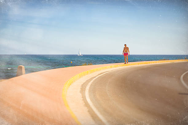 молодой спортивный человек, ходить на фоне парусных лодках плавающий - valencia province spain beach mediterranean sea стоковые фото и изображения